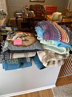 Pile of folded blankets and dog themed pillows displayed on a half wall in a home setting.