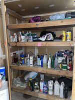 Image of wooden shelves holding various garage and lawn chemicals, spray paint, and other bottles and containers.