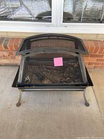 Front angled view of the black metal outdoor chiminea fireplace showing mesh sides, curved legs, and top.