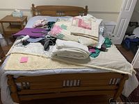 Full wooden bedframe with headboard and footboard covered by textiles.