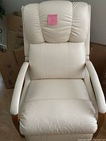 Full front view of beige leather recliner with padded cushions and wood side accents.