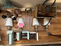 Miscellaneous housewares including two silver three-light sconces, straw scarecrow figurine, hanging decorative bird, leopard print handbag, light green wall organizer, and a floral glass candle holder.