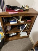 Front view of oak bookcase with various items on top and on shelves