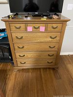 Front view of the oak dresser with TV on top and items on surface.