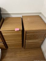 Photo showing two oak filing cabinets side by side with multiple drawers and wood finish.