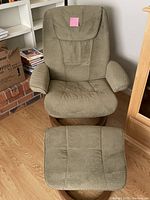 Front view of green upholstered rocker recliner with matching ottoman placed in front of it.