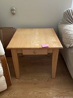 Front view of the maple side table showing drawer and four legs