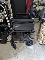 Side view of the black Airgo transport chair showing armrests, rear wheel, and frame details.