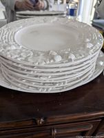 Stack of white ceramic plates showing oak leaf and acorn motif around the edges