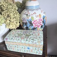 Ginger jar and trinket box displayed side by side on wooden surface with dried hydrangea.