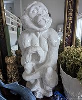 Front view of white glazed terracotta monkey figurine with visible facial details and body posture