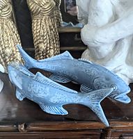 Pair of blue ceramic koi fish figurines placed on a wooden surface, showing detailed view of the blue and white chinoiserie style.