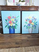 Pair of framed floral paintings on floor showing overall condition and framing