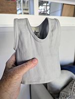 Grey plaster shirt sculpture held in hand, showing front and texture details.