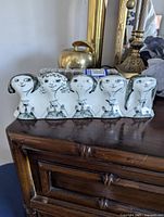 Front view of the ceramic row of six schoolgirls showing detailed faces and black decoration on white ceramic.