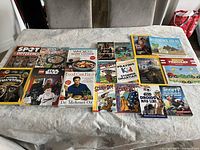 Photo showing an assortment of 22 books laid out on a table, including cookbooks, children's activity books, and National Geographic editions.