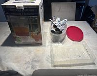 Beverage dispenser box and contents including Christmas crackers, oval container with lid, and paper tray arranged on table