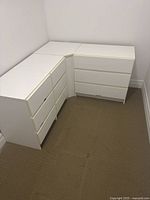 Two white closet cabinets arranged in an L-shaped corner with visible drawer fronts and installed without handles.
