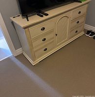 Front perspective of the dresser showing all six drawers and the center cabinet door with black cup pull handles.
