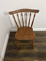 Front view of the medium-toned solid wood desk chair with spindle backrest and contoured seat.