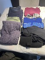 Photo showing folded jeans and sweaters in various colors including black, green, maroon