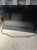 Front view of the black Vizio flat-screen TV on a table with power cord visible.