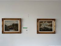Photo showing two framed paintings on a wall: one of a river landscape and one of a sailing ship on rough sea.