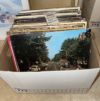 Cardboard box holding multiple Beatles LP records with Abbey Road sleeve visible at front.