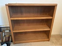 Front view showing three shelves and natural wood grains with rounded edges.