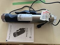 Power Precision Cooker device lying horizontally with power cord and attached clamp, alongside the owner's manual.