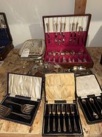Overall photo of the serveware collection including flatware, chafing dish, serving dish, and boxed utensils on a wooden surface.