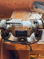 Front view of the Brico electric bench grinder showing the label and grinding wheels with protective tool rests.