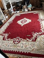 Full view of rug in room showing red field, cream border and overall size