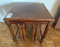 Front view of the largest nesting table showing wood top and turned legs with medallion accents.