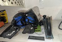 Two electric sanders with dust bags, a manual, and a black handheld rasp on a shelf.