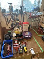 Wide view of the hand tools spread on the table including clamps on the wall, fastener jars on rack, and various hand tools in containers.