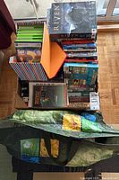 Overhead shot of lot showing striped container with Xbox 360 cases and PC game boxes, Riven box on top, and reusable shopping bag