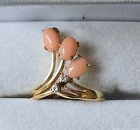 Close-up front view of gold plated ring with three pink oval stones and two small clear stones.