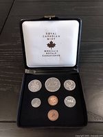 Full view of the black protective case open showing eight uncirculated coins arranged inside with the Royal Canadian Mint logo on the case lid.