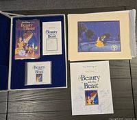Photo showing the open deluxe collector's edition box with VHS tape, soundtrack CD, booklet, and lithograph spread out on a table.