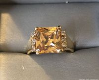 Front view of sterling silver ring with large square-cut amber stone and small clear stones on sides.