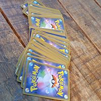 Stack of Pokémon cards showing the back side with typical blue background and Poké Ball design.