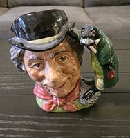 Front view of the Royal Doulton Toby Jug showing detailed facial features of a man wearing a black top hat, red scarf, and a green walrus on the shoulder handle.