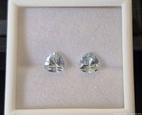 Two trillion cut sky blue topaz gemstones displayed in a box, showing their color and cut.