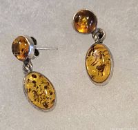 Close-up of amber and sterling silver earrings showing oval and round amber stones set in silver and butterfly posts.