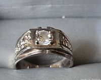 Clear oval center stone set with textured silver band, showing overall design and setting.