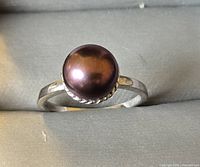 Front view of the sterling silver ring with a dark pearl centerpiece.