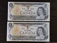 Front side of two Canadian one dollar bills showing Queen Elizabeth II portrait, serial numbers, and coat of arms.