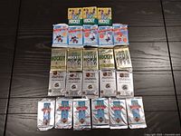 All 24 unopened packs arranged in five rows on dark floor