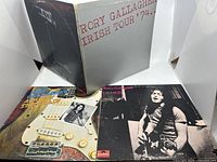 Photo showing the three Rory Gallagher LP album covers including Irish Tour '74 gatefold album, debut 1971 album with guitar cover, and Against The Grain cover featuring black and white photo of Rory.
